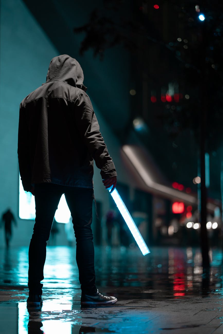 man wearing black hoodie standing on concrete pavement at night